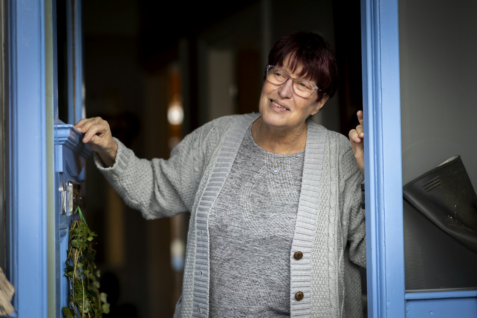 Homeowner opening her front door and greeting a visitor